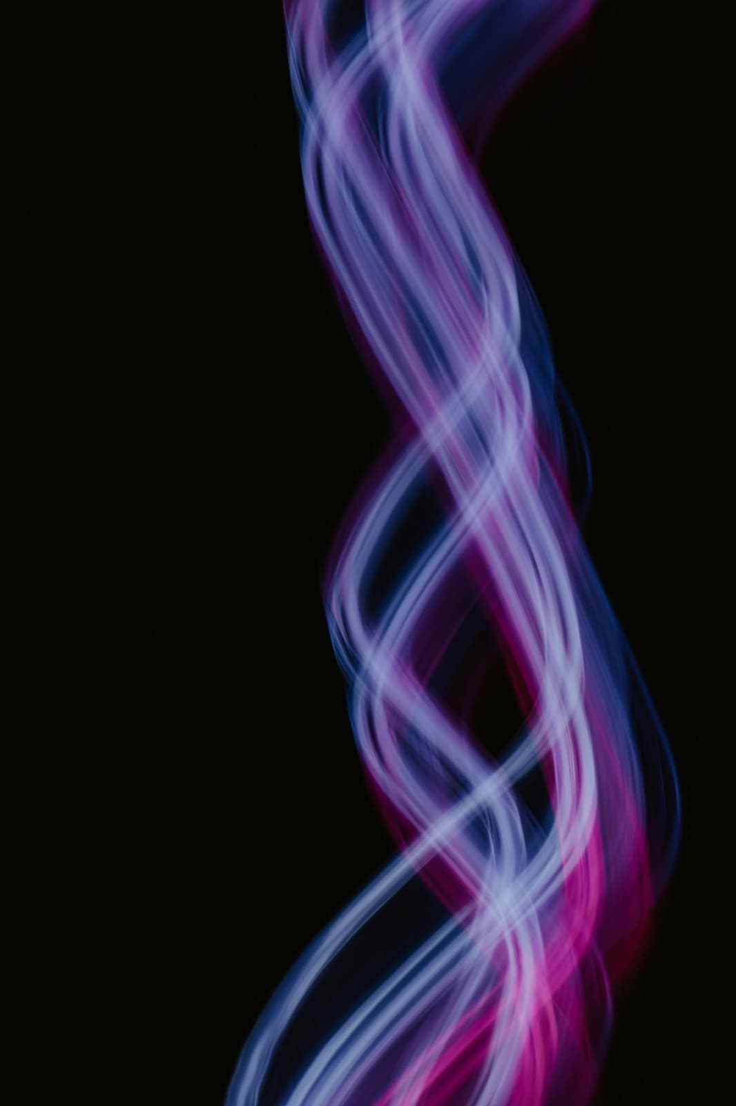 Purple and blue strands of light twisting in the dark